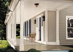 the front porch of a house with blue shutters and two chairs on either side