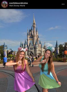 two girls in front of a castle posing for the camera with their hands up and pointing