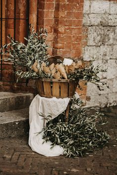 a basket filled with olives sitting on top of a stone floor next to a brick wall