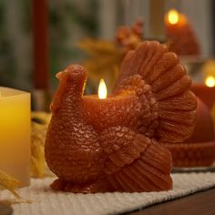 a close up of a chicken on a table near candles