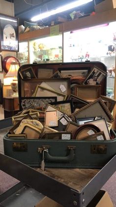 an open suit case filled with assorted items on top of a wooden table in a store