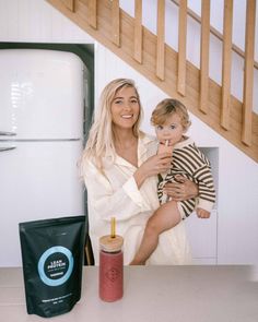 a woman holding a baby in her arms next to a coffee bag and some food