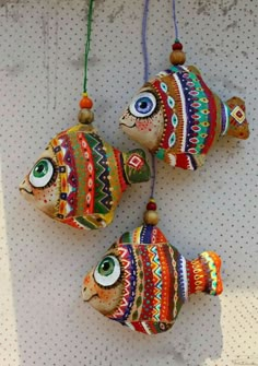 three colorful fish ornaments hanging on a wall