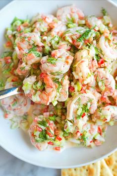 a white bowl filled with shrimp salad next to crackers