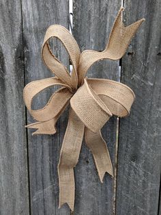 a brown bow hanging on the side of a wooden fence next to a metal hook