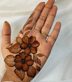 a woman's hand with flowers on it and leaves painted on the palm area