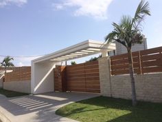 a house with a fence and palm trees in the front yard