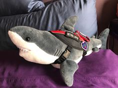 a stuffed shark laying on top of a purple pillow