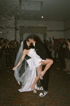 a bride and groom kissing on the dance floor with bubbles in the air behind them