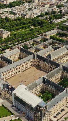 an aerial view of a large building in the middle of a city with lots of trees