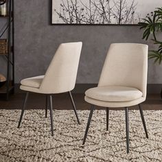 two beige chairs sitting on top of a rug