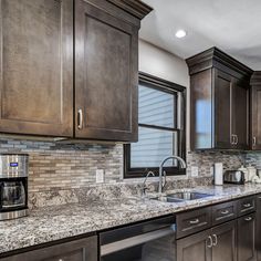 a kitchen with granite counter tops and stainless steel appliances in the center, along with dark wood cabinets