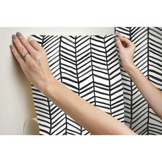 two hands are holding onto a black and white wallpaper with an arrow pattern on it