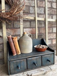 an old dresser with books and a vase on it next to a dried twig