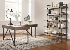 a room with a desk, bookshelf and lamp on the floor in front of a window