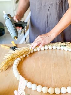 a woman is making a bead necklace on a table