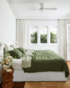 a bedroom with white walls and green bedding in the corner, along with wooden flooring