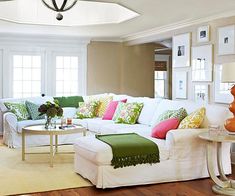 a living room filled with white furniture and lots of pillows on top of it's couches