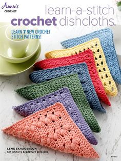 four crochet dishcloths on a table with a cup and saucer in the background