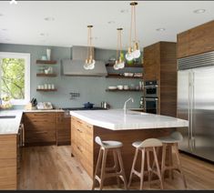 a kitchen with an island and two stools in front of the counter top area