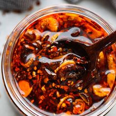 a glass jar filled with food and a wooden spoon on top of the jar is full of liquid