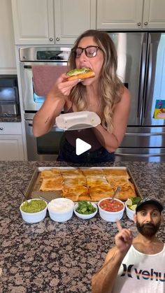 a man and woman sitting at a kitchen counter eating food from plates in front of them