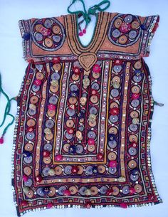 Traditional woman's blouse, hand embroidered, metallic threads, pompoms, beads, hand made glass mirror pieces (shisha). This is a traditional dress/blouse from Gujerat, probably Meghwal people. These are alwaya backless, the garment is fastened with ties at the back of the neck and around the waist - a photograph shows one being worn. The bare back is completely covered by the large headshawl. The back of the short sleeves are made of red cotton fabric decorated with a panel of an interlacing st Traditional Festival Dresses With Motifs, Festive Motif Kaftan For Festivals, Bohemian Ceremonial Choli, Bohemian Choli For Ceremonial Occasions, Folk Style Traditional Wear With Zari Work For Festivals, Bohemian Multicolor Choli For Ceremonial Occasions, Traditional Multicolor Kaftan With Mirror Work, Traditional Kaftan With Mirror Work For Festivals, Ceremonial Dresses With Mirror Work