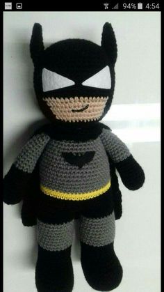 a crocheted batman stuffed animal sitting on top of a white table next to a wall