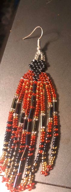 an orange and black beaded earring on a table