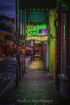 the neon sign for voodoo blues is lit up at night on an alleyway in new orleans