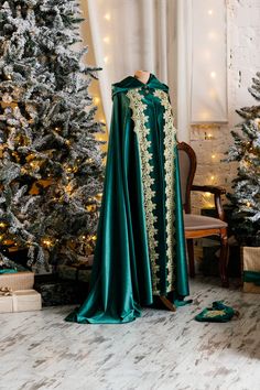 there is a green cape on display in front of the christmas tree and other decorations