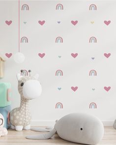 a stuffed animal next to a wall with hearts and rainbows on it