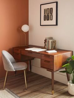 a desk with a chair, lamp and pictures on the wall