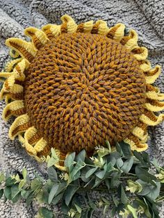 a yellow knitted sunflower laying on top of a blanket