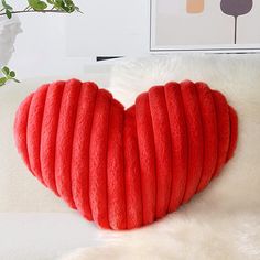 a red heart shaped pillow sitting on top of a white couch