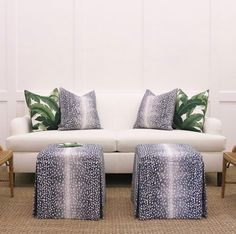 a white couch sitting next to two chairs and a footstool on top of a rug