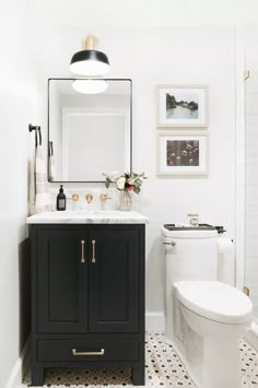 a white and black bathroom with pictures on the wall above the sink, toilet and vanity