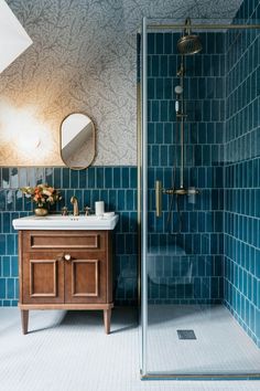 a blue tiled bathroom with a wooden vanity and shower stall next to the sink area