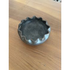 a metal bowl sitting on top of a wooden table next to a black cat toy