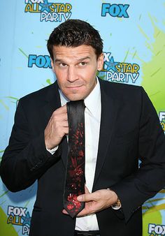 a man in a suit holding a tie up to his face with an angry look on his face