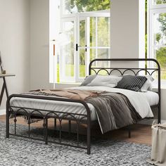 a metal bed frame in a bedroom with windows and rugs on the floor next to it