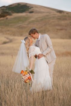 a bride and groom standing in tall grass