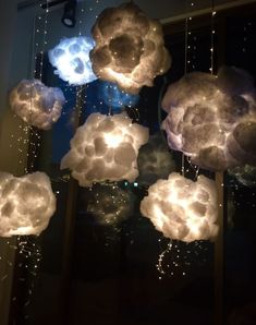 some clouds that are hanging from the ceiling in front of a window with lights on them