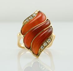 Fire Ring, Flame Ring, Orange Ring, Carnelian Ring, Diamond Ring, Vintage Ring, Gold Ring, Square Band, Gold Band, Cocktail Ring. This one of a kind estate ring is crafted in solid 18K Yellow Gold. The setting with natural Carnelian is reminiscent of flames. Absolutely stunning! Six diamonds total .13 carat of VS1 clarity and H color. The square band is 17mm x 16mm inside, it is hard to know the size. We would say the size is around 7-7.25 and the ring can easily be resized. The top of the ring Yellow Gold Carnelian Jewelry With Polished Finish, Elegant Carnelian Yellow Gold Rings, Elegant Carnelian Ring In Yellow Gold, Elegant Yellow Gold Carnelian Ring, Heirloom Carnelian Yellow Gold Rings, Luxury Carnelian Ring For Formal Occasions, Yellow Gold Carnelian Wedding Jewelry, Elegant Carnelian Rings With Polished Finish, Luxury Carnelian Ring Jewelry