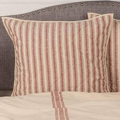 two red and white striped pillows sitting on top of a bed next to a headboard