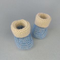 two knitted blue and white baby booties sitting on top of a gray surface