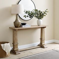 a wooden table with a mirror on it next to a lamp and potted plant