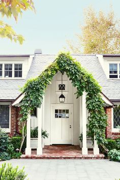 a white house with ivy growing all over it's front door and porch area