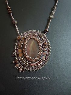 a beaded necklace with an oval shaped stone in the center and beads around it