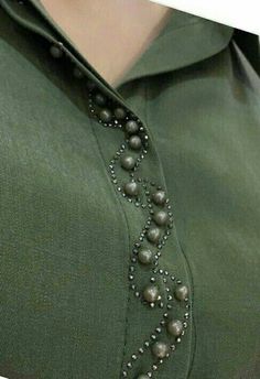 a woman wearing a green shirt with beads on it